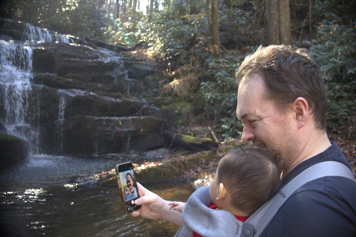 Holding my daughter in a carrier beside a waterfall